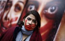 Une militante de l'ONG Rio de Paz devant une une exposition montrant des femmes tachées de sang pour