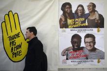 Un homme passe devant une affiche lors d'une manifestation contre le FN, place de la République à Pa