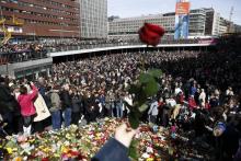 Des personnes se rassemblent devant des fleurs pour rendre hommage aux victimes de l'attentat de Sto