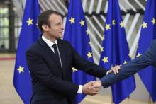 French President Emmanuel Macron shake hands as he arrives at the Europa Building, the main headquar