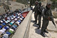 Une palestinienne manifeste et brandit un exemplaire du Coran devant un membre des forces de sécurit