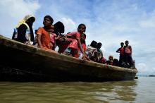 Le 3 septembre 2017, des réfugiés Rohingyas transportent une femme âgée le long d'"un chemin près de