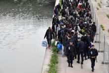 Des migrants font la queue pour monter à bord d'autocars lors de l'évacuation du campement du Millénaire, à Paris, le 30 mai 2018